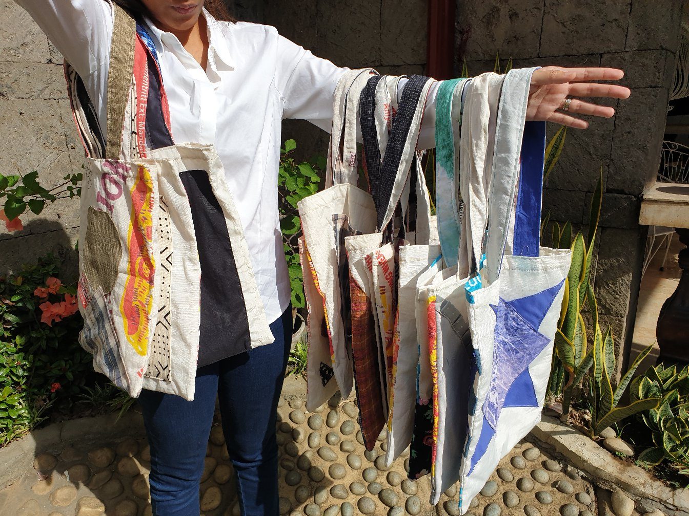 A maker holding an armful of finished katsa tote bags